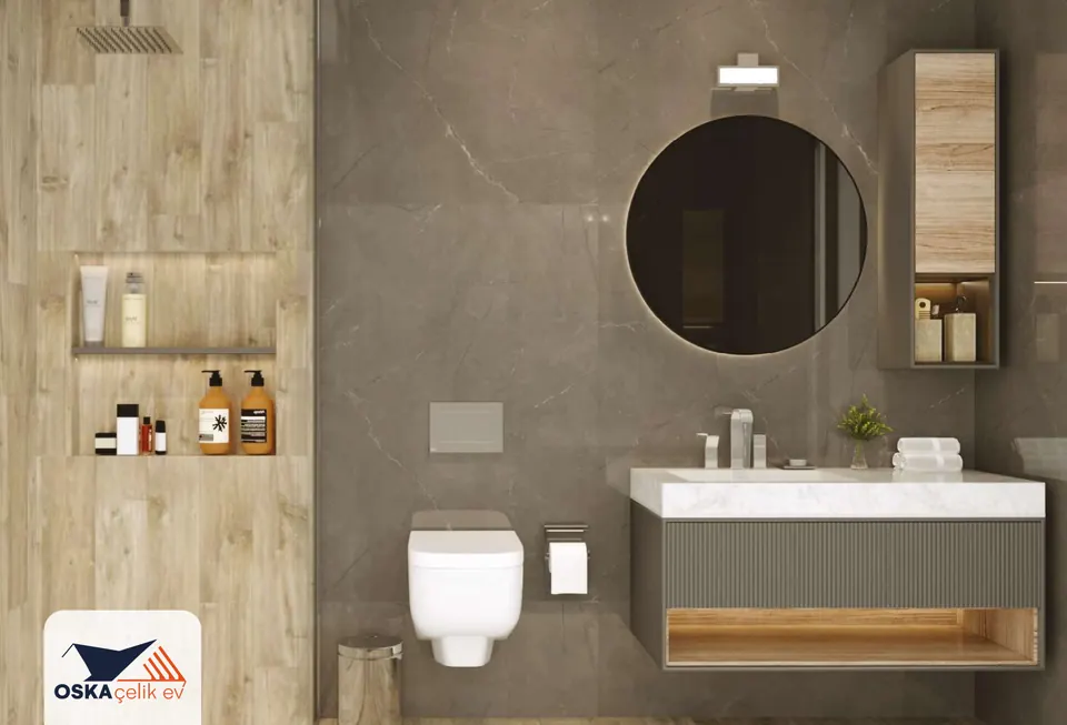 Ahşap görünümlü duvarda raflı nişi ve yağmurlama duşu, mermer desenli gri duvarda yuvarlak aynası, asma klozeti ve ahşap raflı lavabo dolabı bulunan banyo.