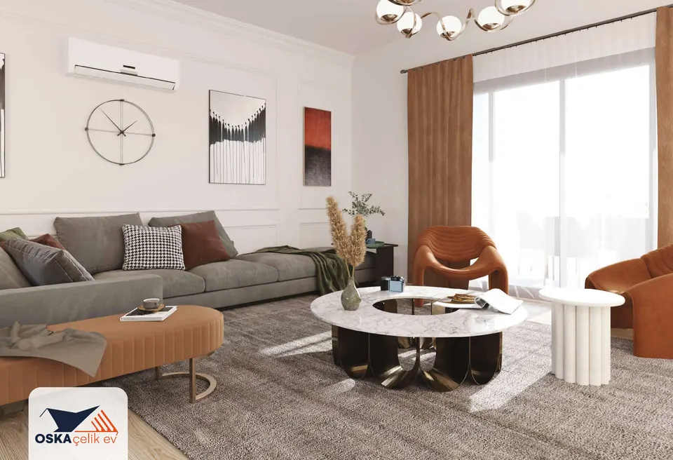 Gri köşe koltuk, turuncu puf, yuvarlak orta sehpa ve turuncu koltukların bulunduğu salon; geniş pencere, perde ve duvarda split klima